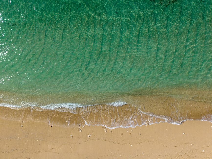 Breathtaking aerial view of emerald waters and sandy beach in Bali, Indonesia.